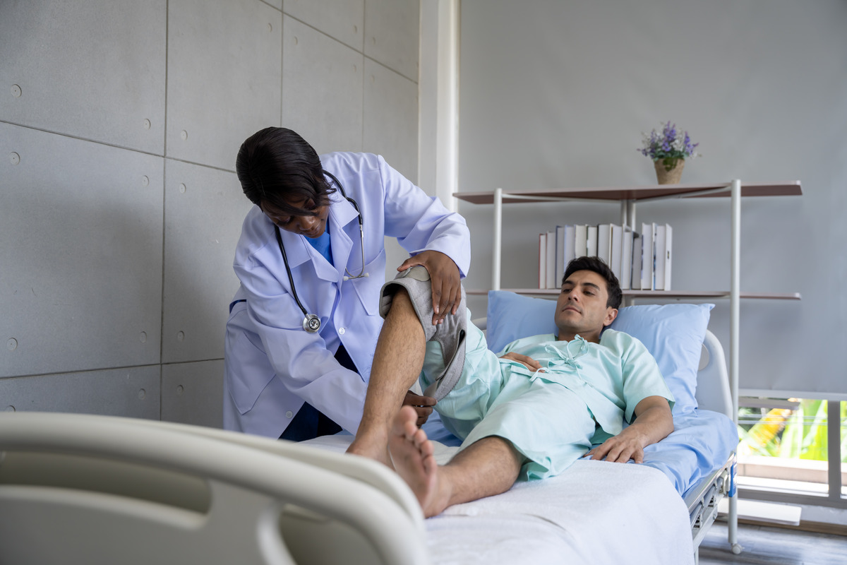 Sesión de fisioterapia ortopédica mostrando a un profesional de la salud tratando una lesión de rodilla de un paciente en una clínica médica