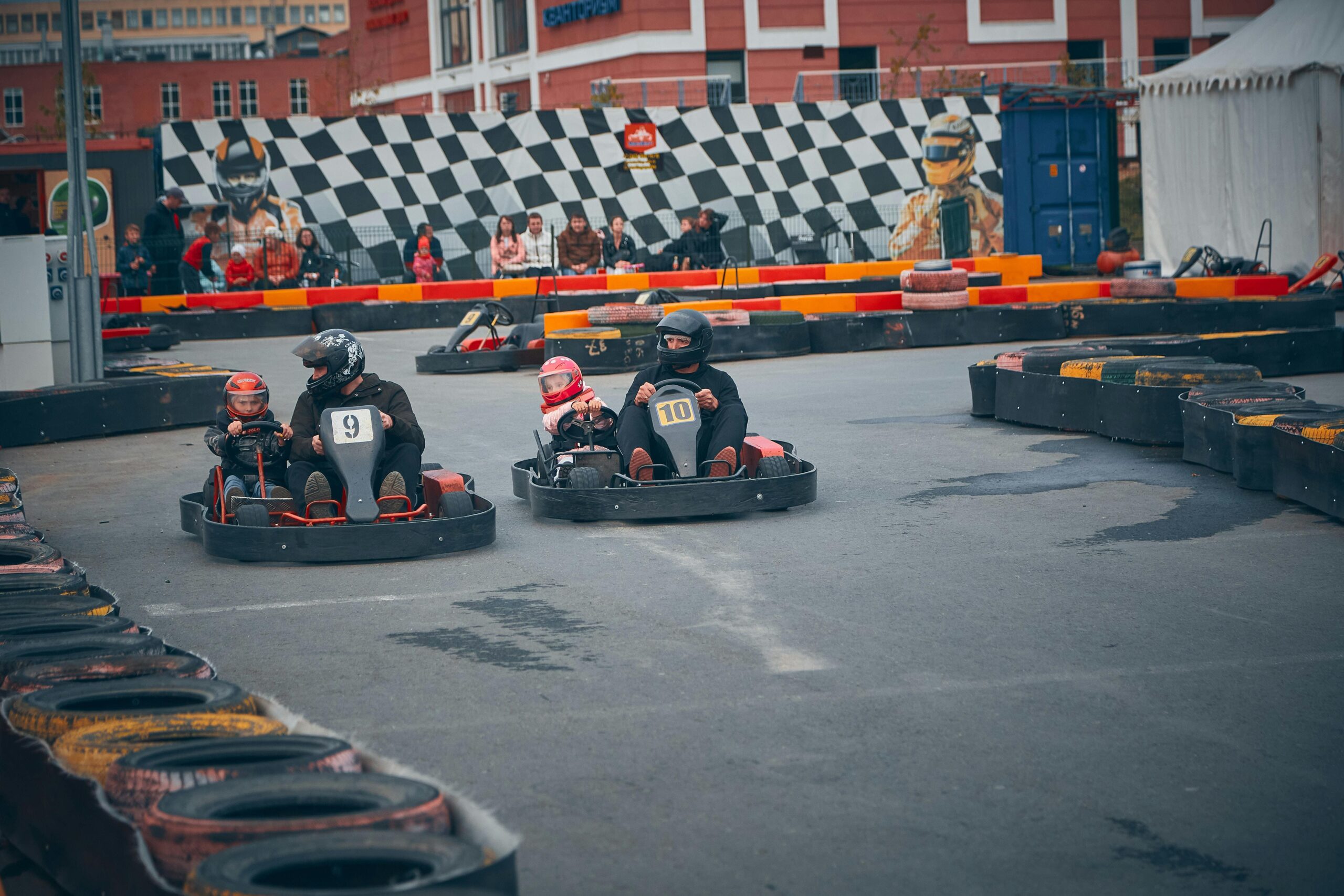 Adultos y niños corriendo en go-karts en una pista al aire libre con barreras de seguridad de neumáticos