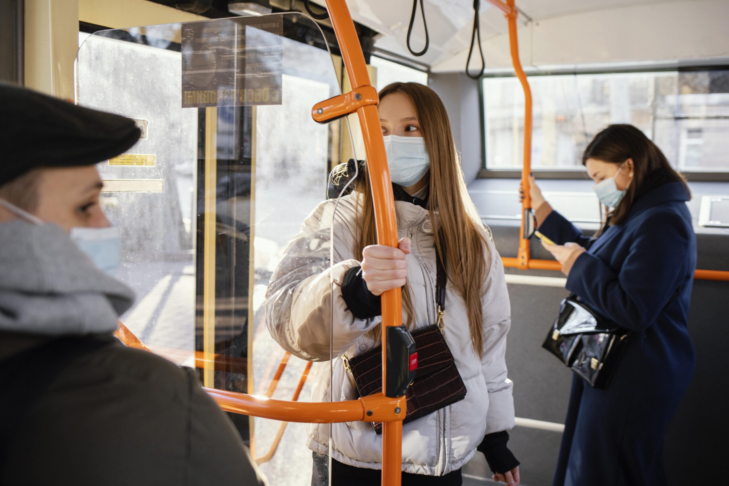 Usuarios que usan mascarillas mientras están de pie en un autobús público y se sujetan de los pasamanos
