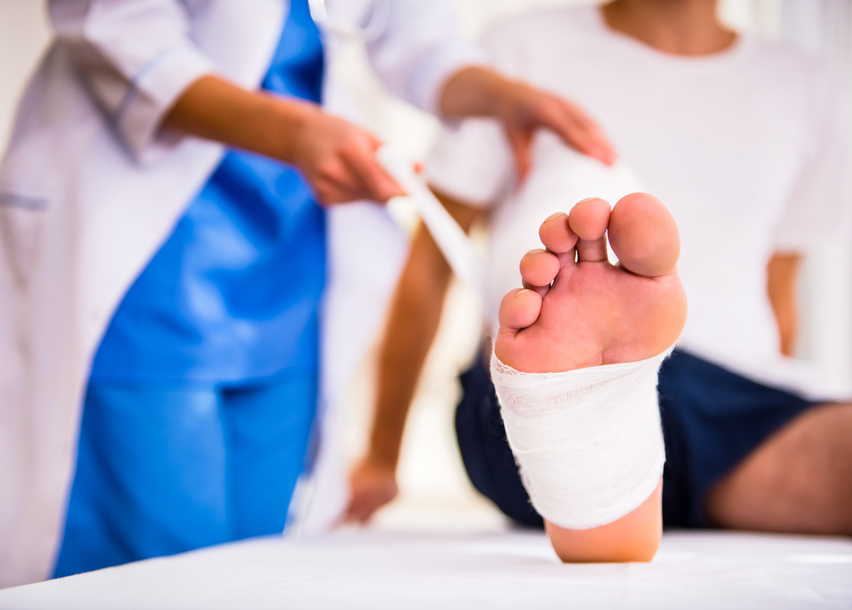 Paciente con el pie vendado recibiendo atención médica, representando tratamiento de lesiones, recuperación y rehabilitación después de un accidente