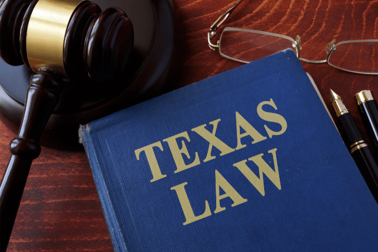 Libro de leyes de Texas con un mazo de juez, lentes y pluma sobre un escritorio de madera, representando el sistema legal y servicios legales en Texas