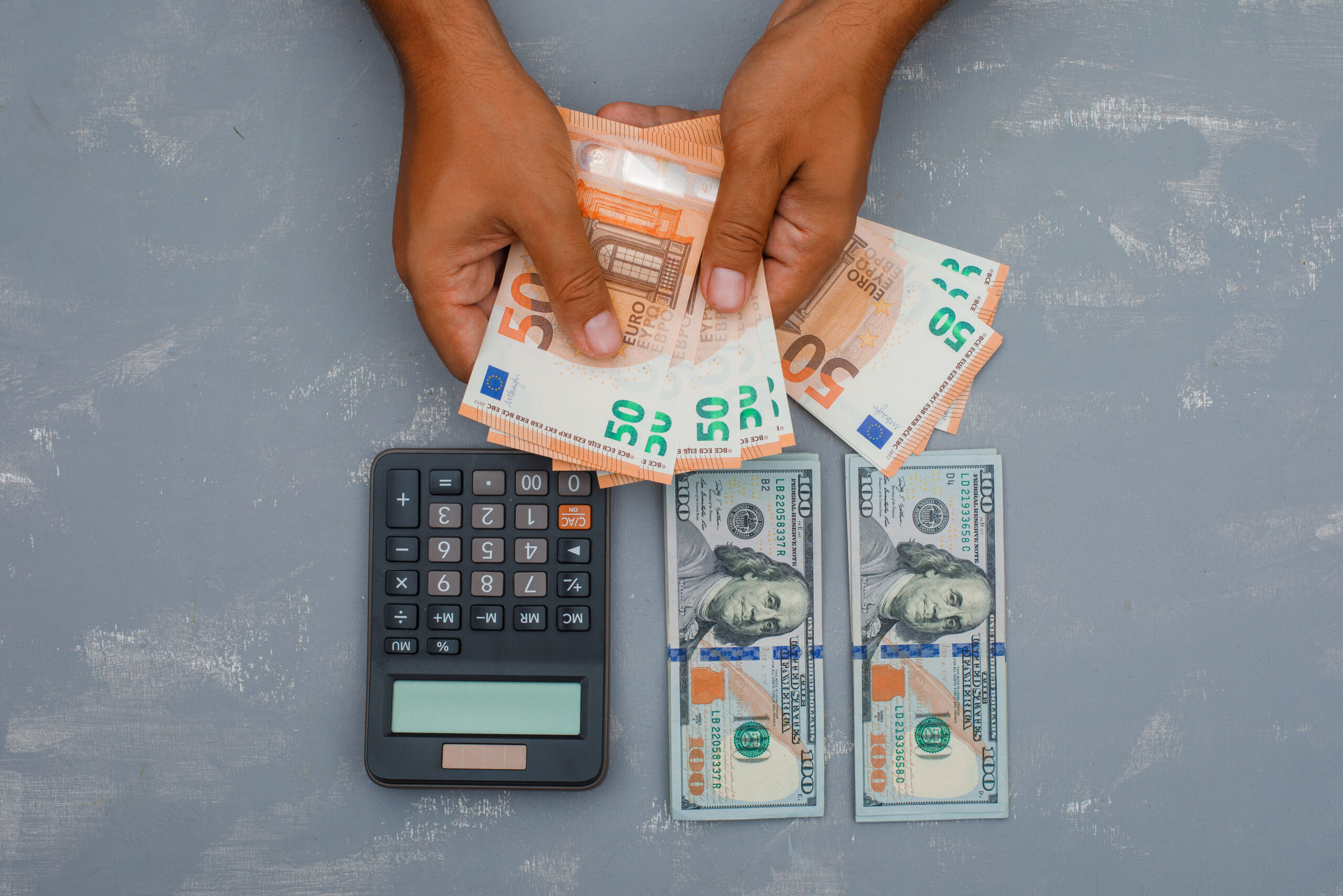 Manos contando dinero en efectivo junto a una calculadora y billetes, representando compensación financiera, daños económicos, salarios perdidos, cálculos de acuerdos y pagos en reclamos por lesiones personales.