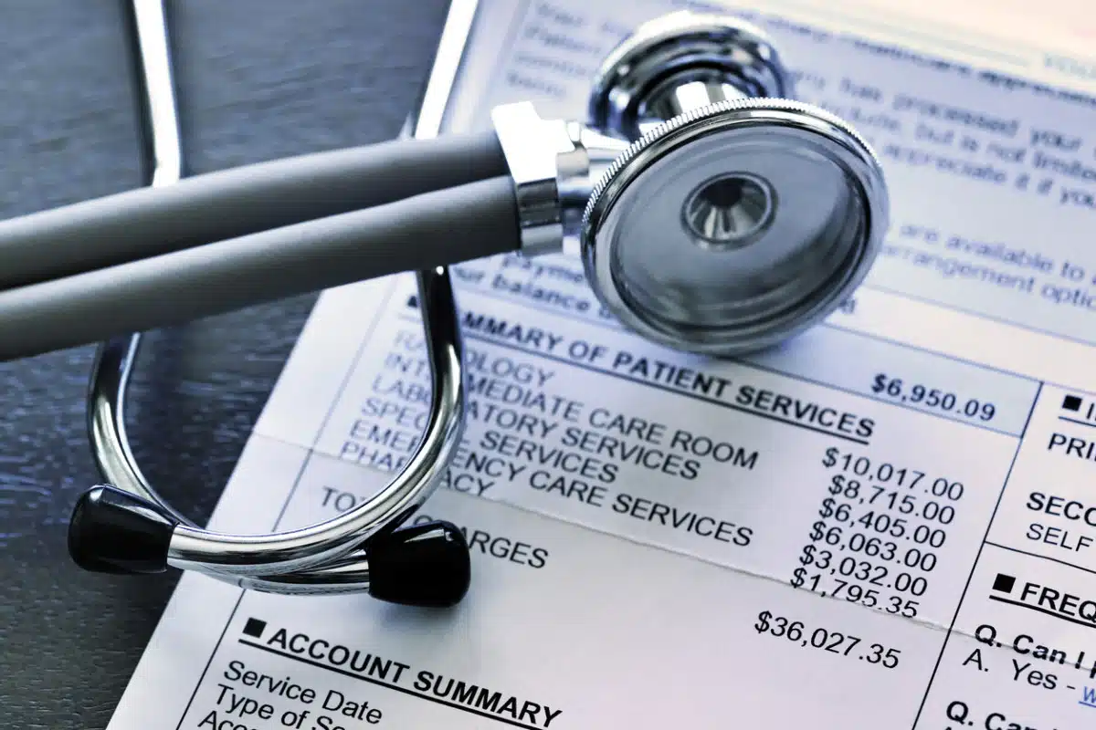 Estetoscopio sobre una factura médica detallada que muestra cargos por servicios de salud, representando gastos médicos, facturación hospitalaria, reclamos de seguros y compensación por lesiones personales.