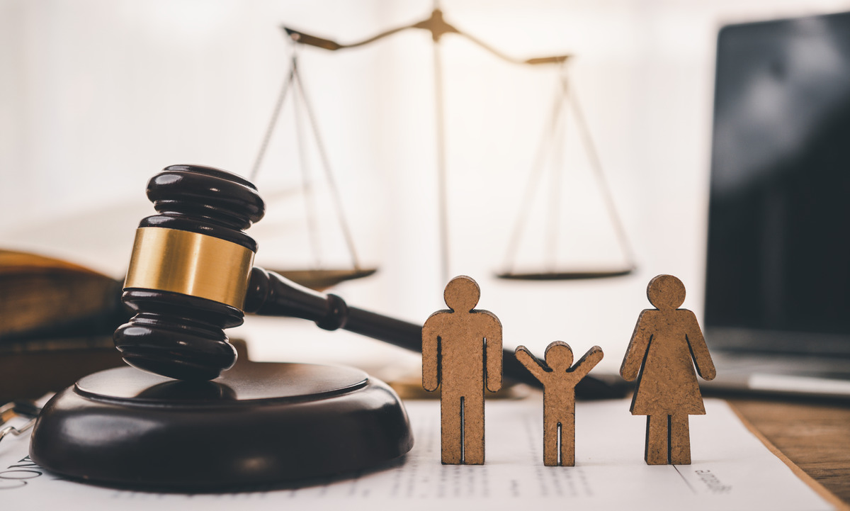 Concepto de derecho familiar con mazo de juez, balanza de la justicia y figuras de madera de una familia, representando custodia de menores, procesos de divorcio, derechos parentales, tribunales familiares y servicios legales para familias