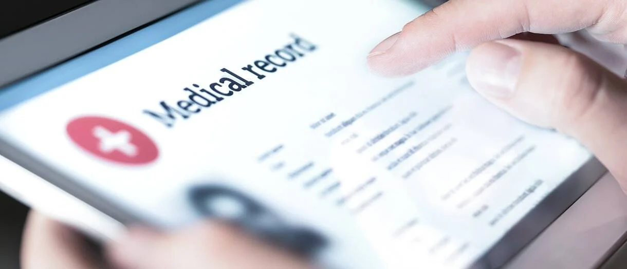 Persona revisando registros médicos digitales en una tableta, representando documentación médica, evidencia de lesiones, historial médico y registros utilizados en reclamos por lesiones personales y casos legales