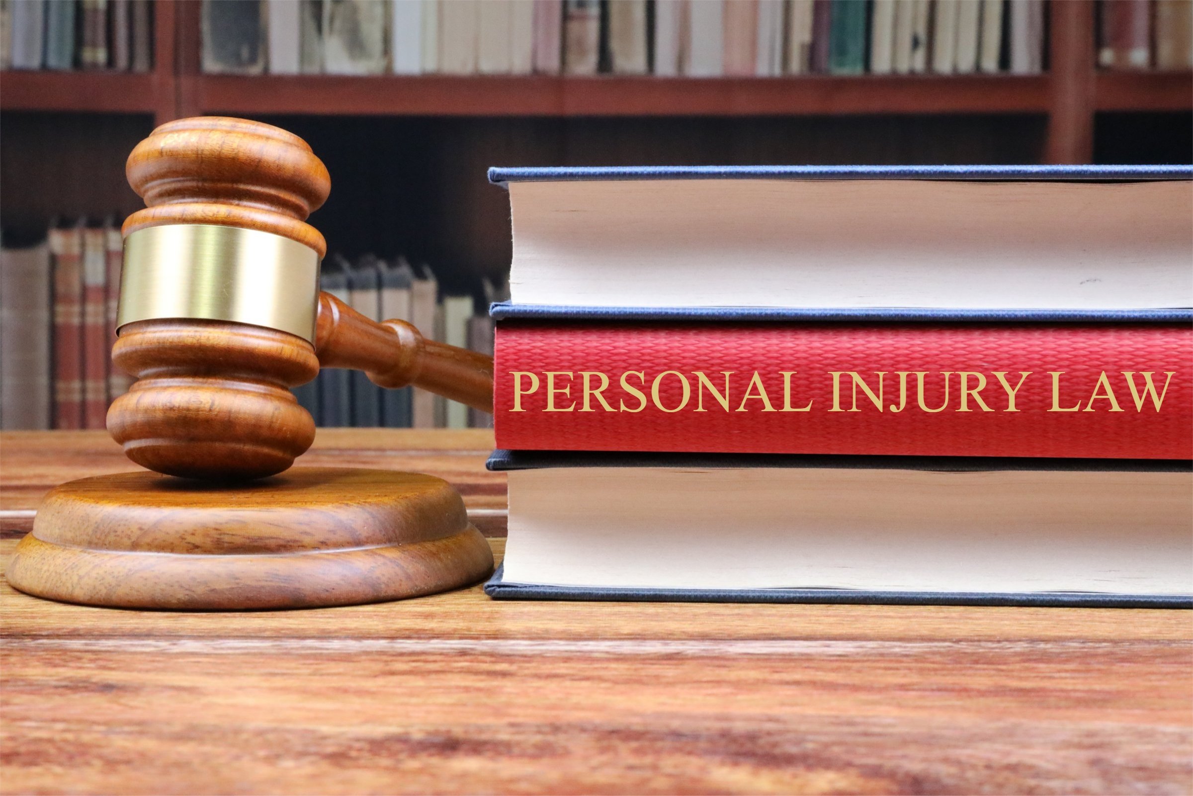 Libro de derecho de lesiones personales junto a un mazo de juez sobre un escritorio de tribunal, representando reclamos por lesiones personales, representación legal, compensación por accidentes y servicios legales para víctimas lesionadas