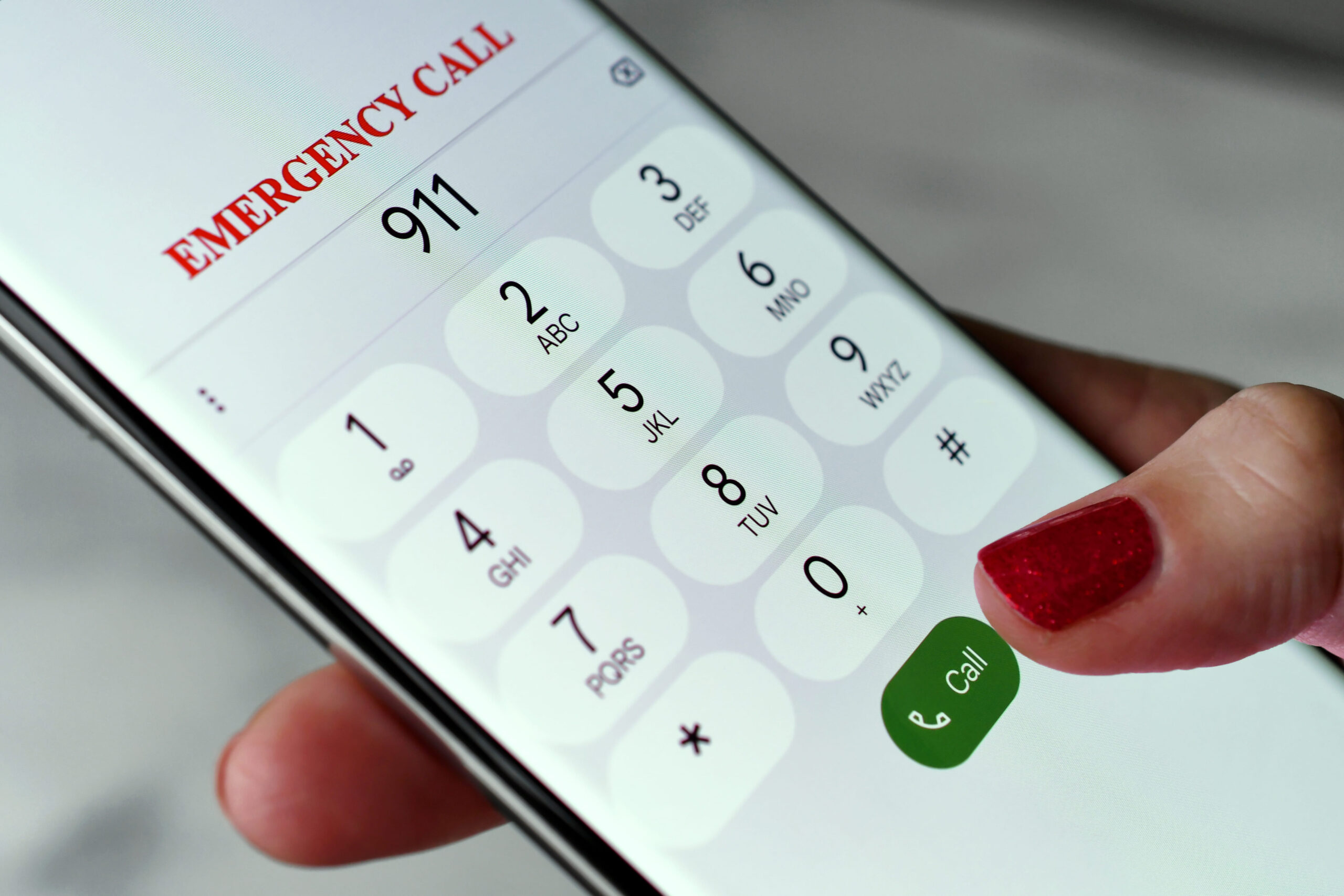 Persona marcando al 911 desde un teléfono inteligente después de un accidente, representando la respuesta ante emergencias, el reporte de un accidente automovilístico, la solicitud de asistencia médica inmediata y los pasos esenciales después de un accidente de tránsito.