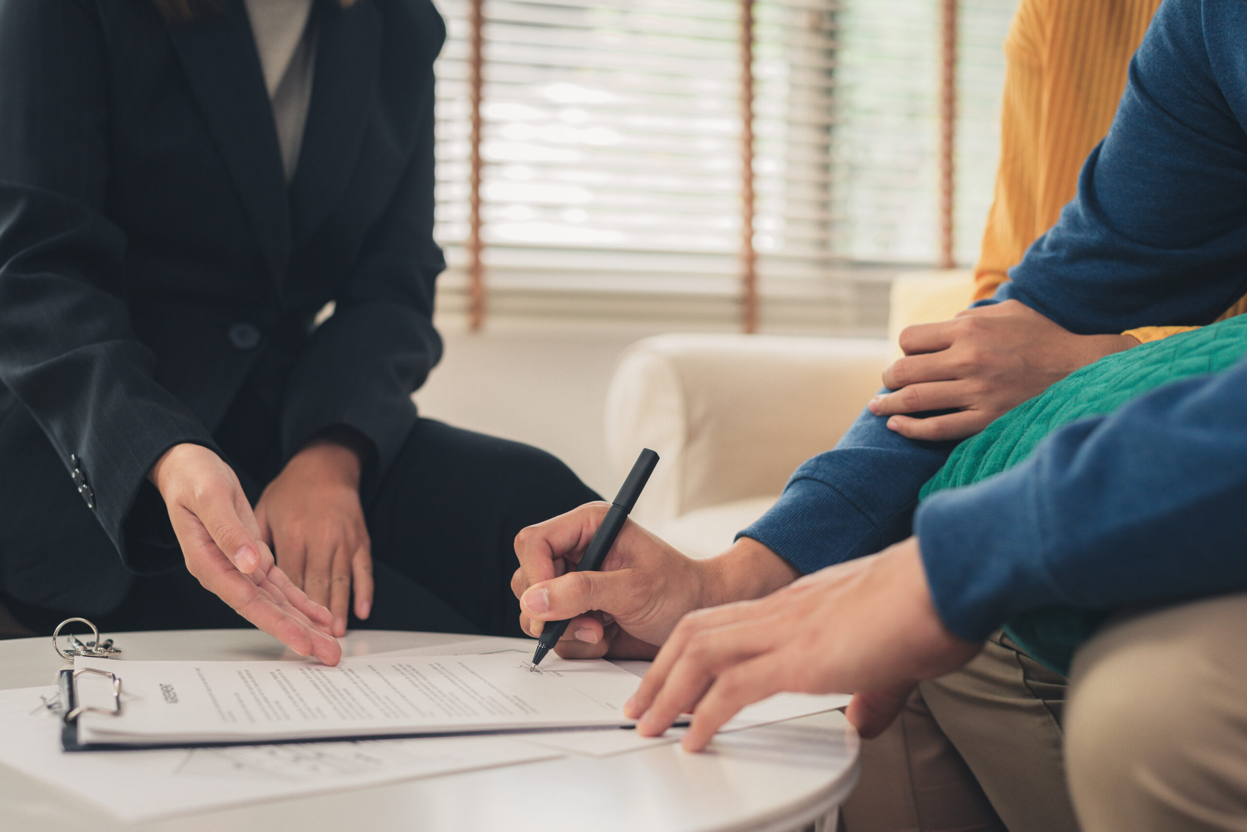 Familia reunida con un abogado mientras firma documentos legales, representando una consulta legal, firma de documentos, orientación jurídica y servicios legales