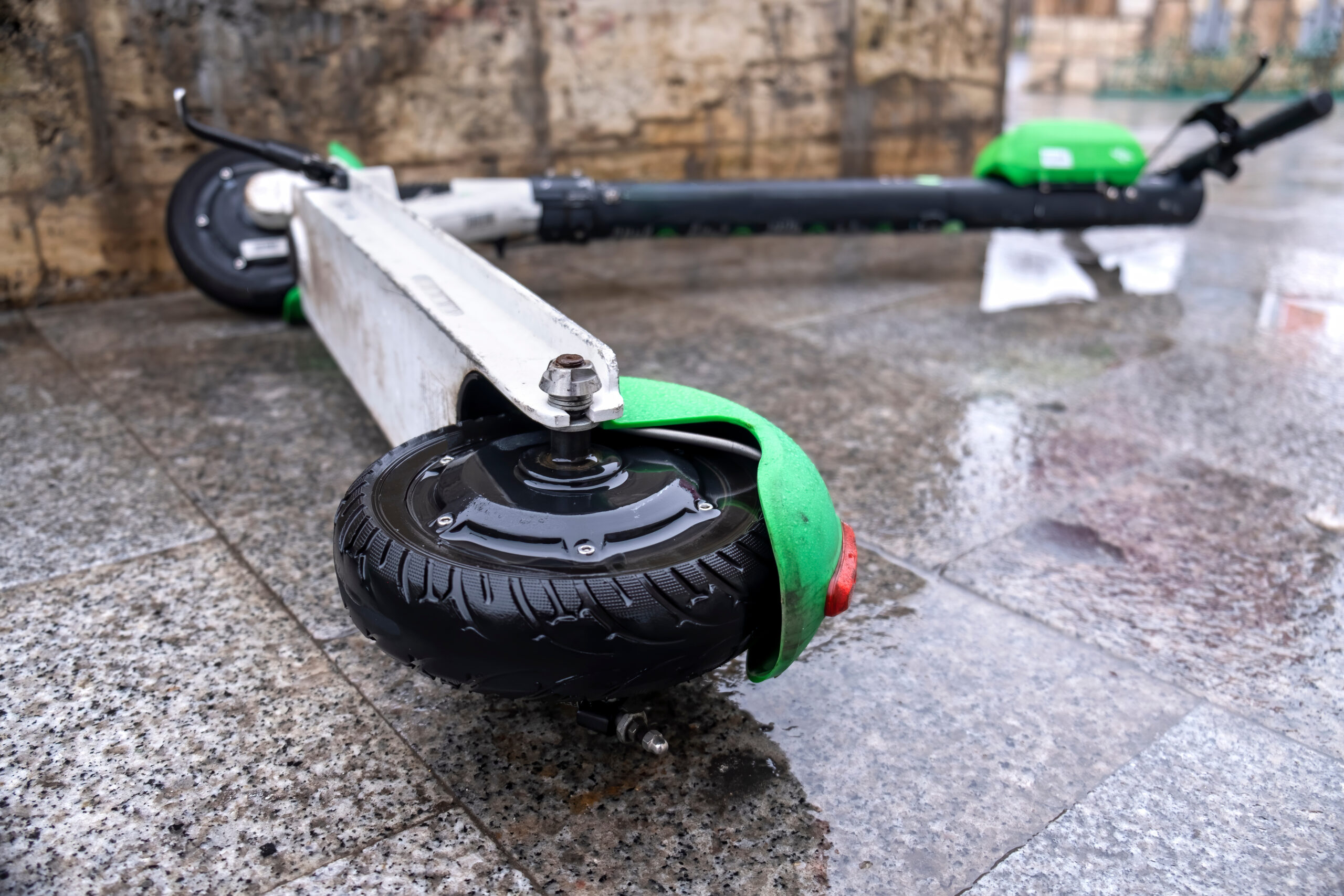 Scooter eléctrico dañado sobre pavimento mojado después de un accidente, representando choques de e-scooters, lesiones de conductores, peligros del transporte urbano y reclamos por lesiones personales relacionados con scooters eléctricos