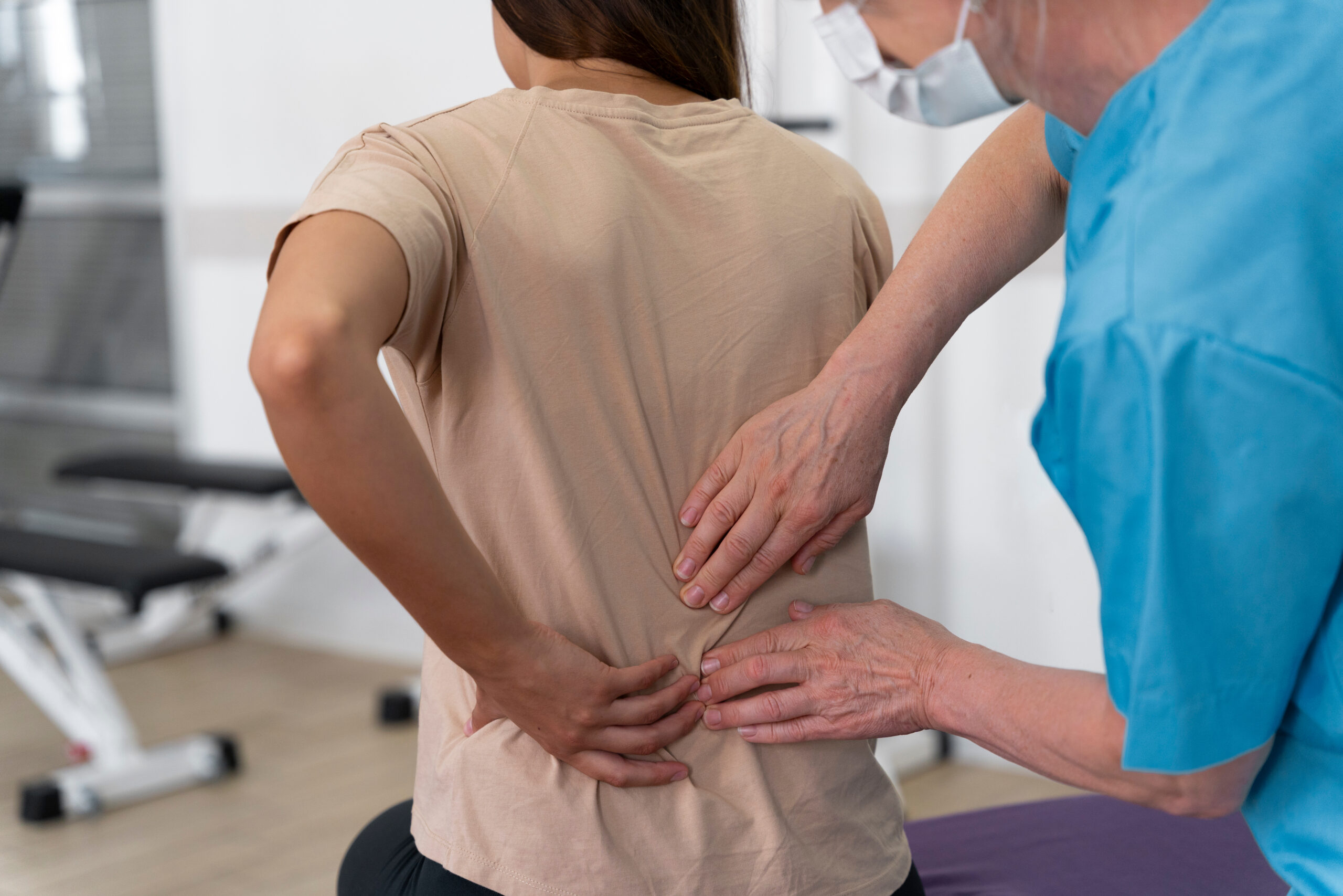 Profesional de la salud examinando la parte baja de la espalda de un paciente durante una sesión de fisioterapia, representando tratamiento de lesiones de espalda, rehabilitación, manejo del dolor crónico y recuperación después de un accidente o lesión personal